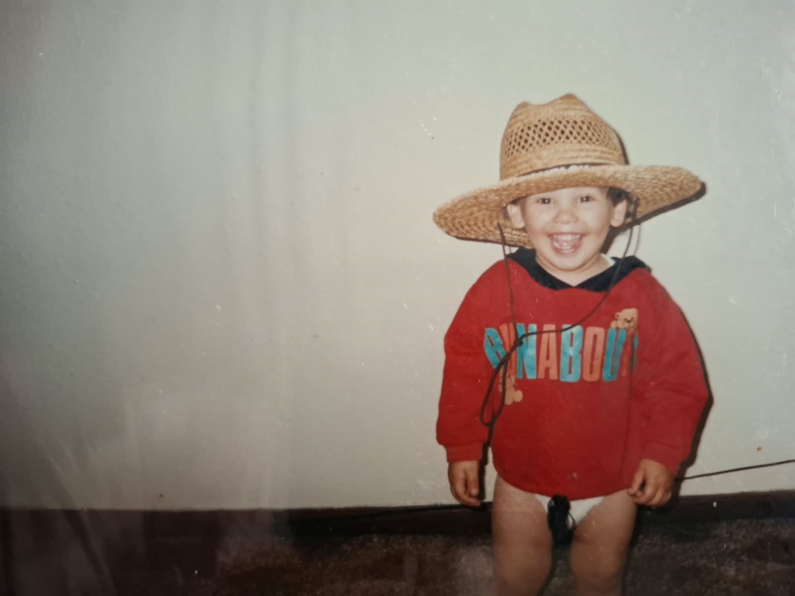 Mikhail as a child, smiling in a straw hat